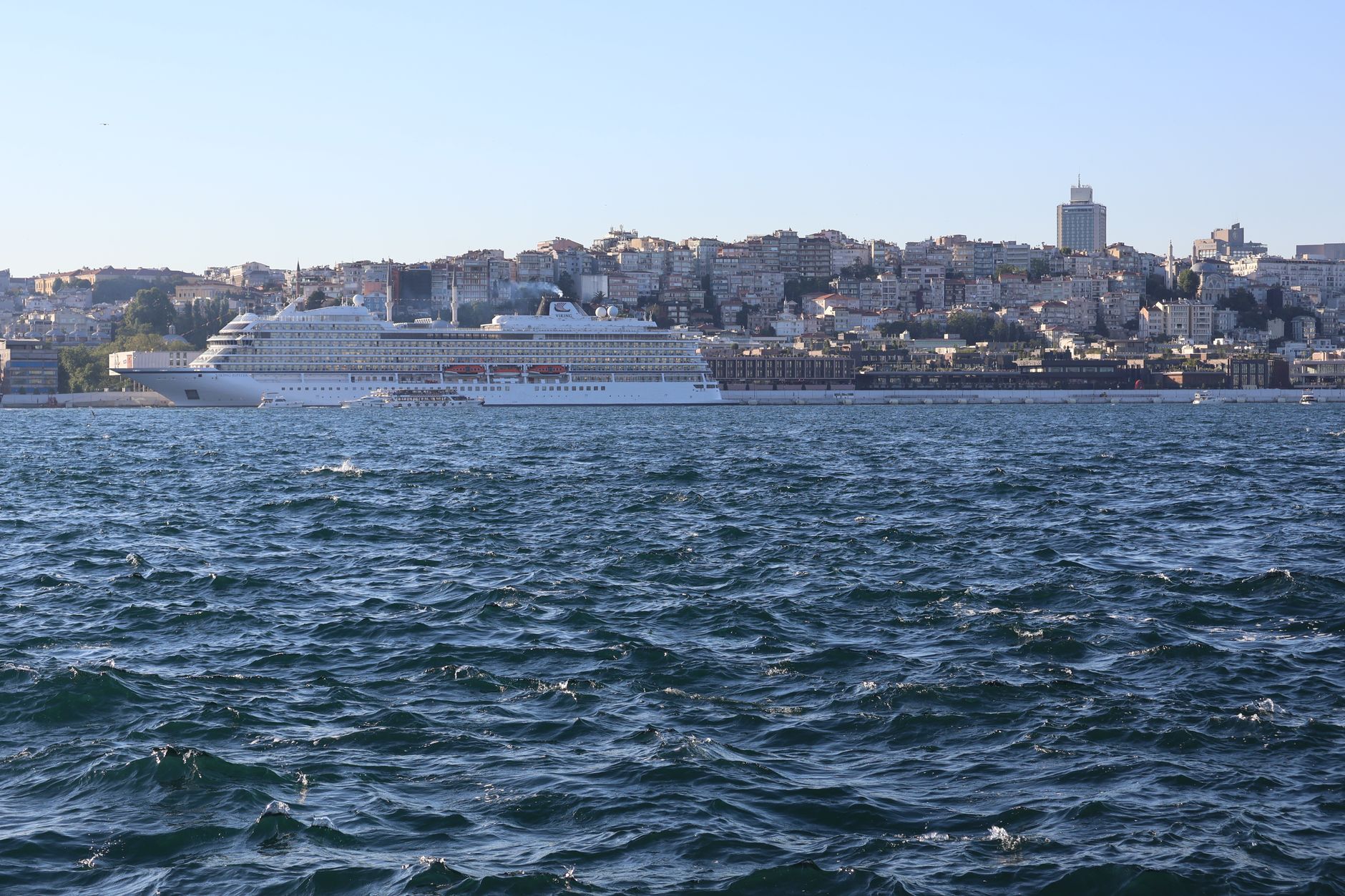 A cruise ship sails through the Bosphorus with Istanbul's skyline in the background.