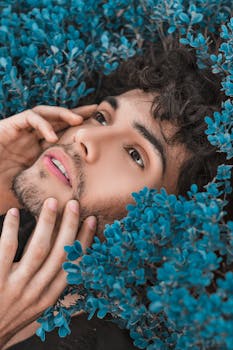 一个男人的特写肖像被充满活力的蓝色花朵环绕，透出一种宁静的氛围