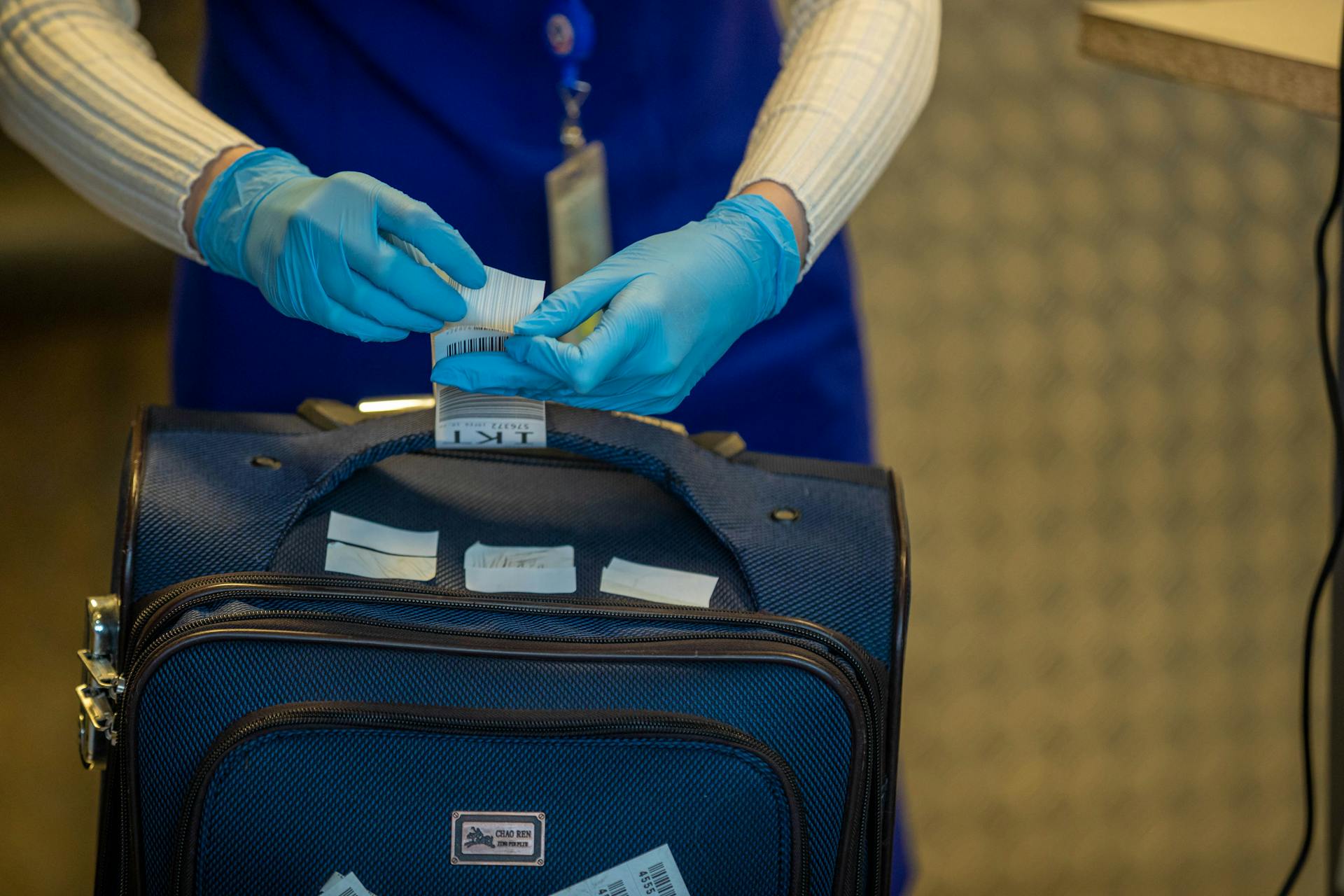 Close-up of airport security process with gloved hands inspecting luggage tags.