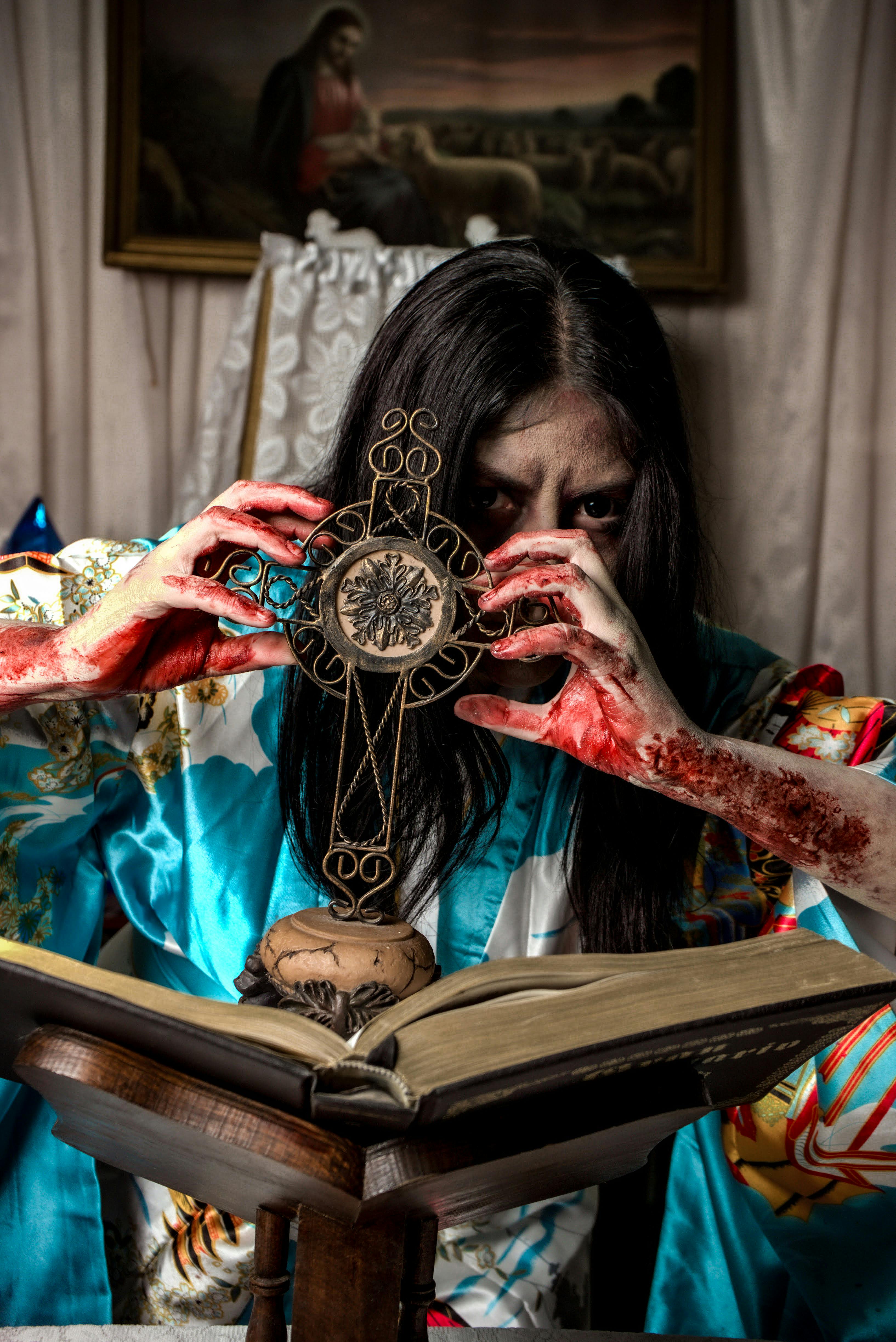A haunted figure performs a ritual with a gothic cross, surrounded by blood and an open book.