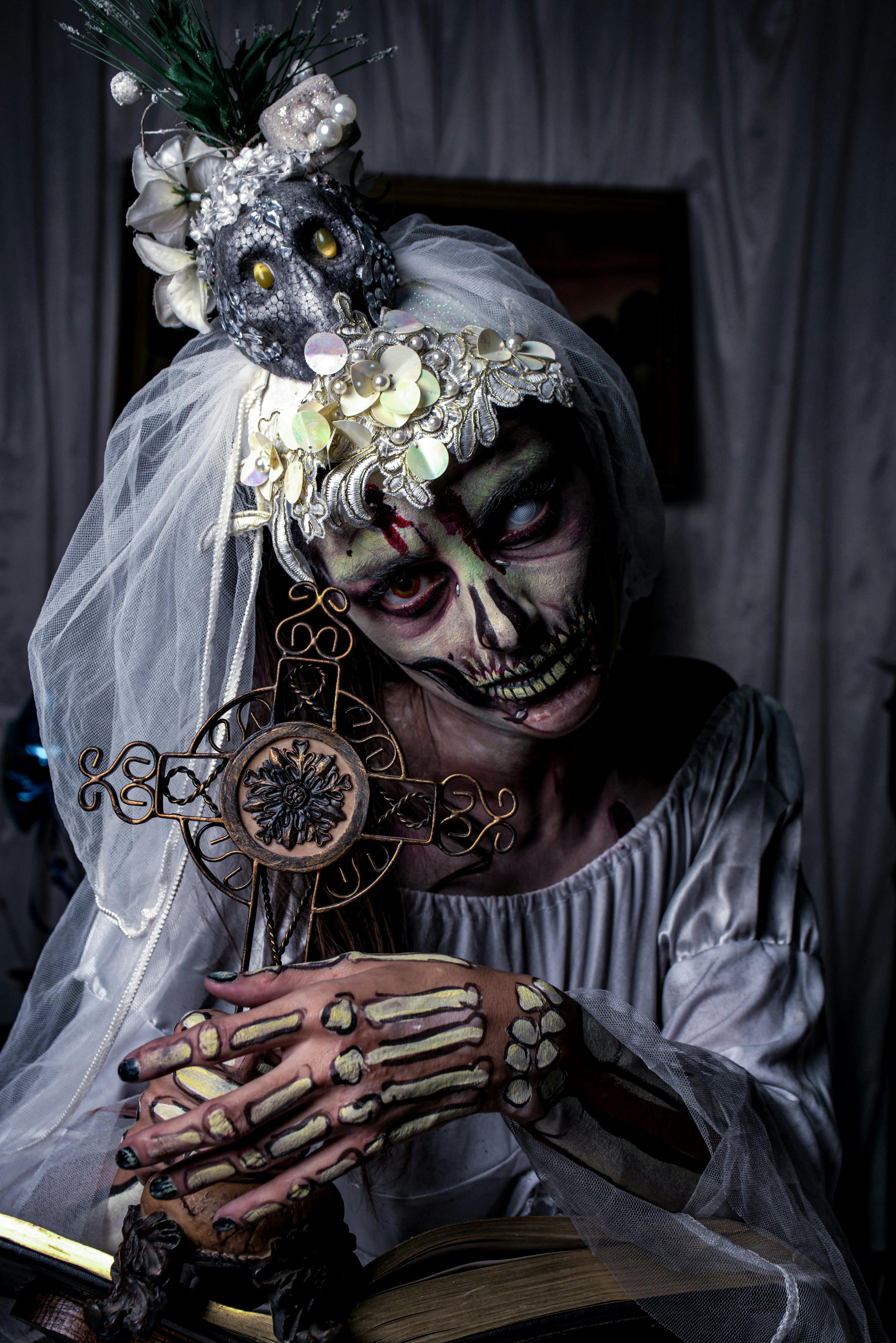 Ücretsiz İskelet makyajlı, süslü haç tutan gotik gelin, ürkütücü ve kasvetli bir atmosfer. Stok Fotoğraflar