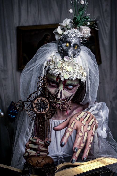 Free A haunting image of a spooky bride holding a cross, adorned with a skull headpiece. Stock Photo