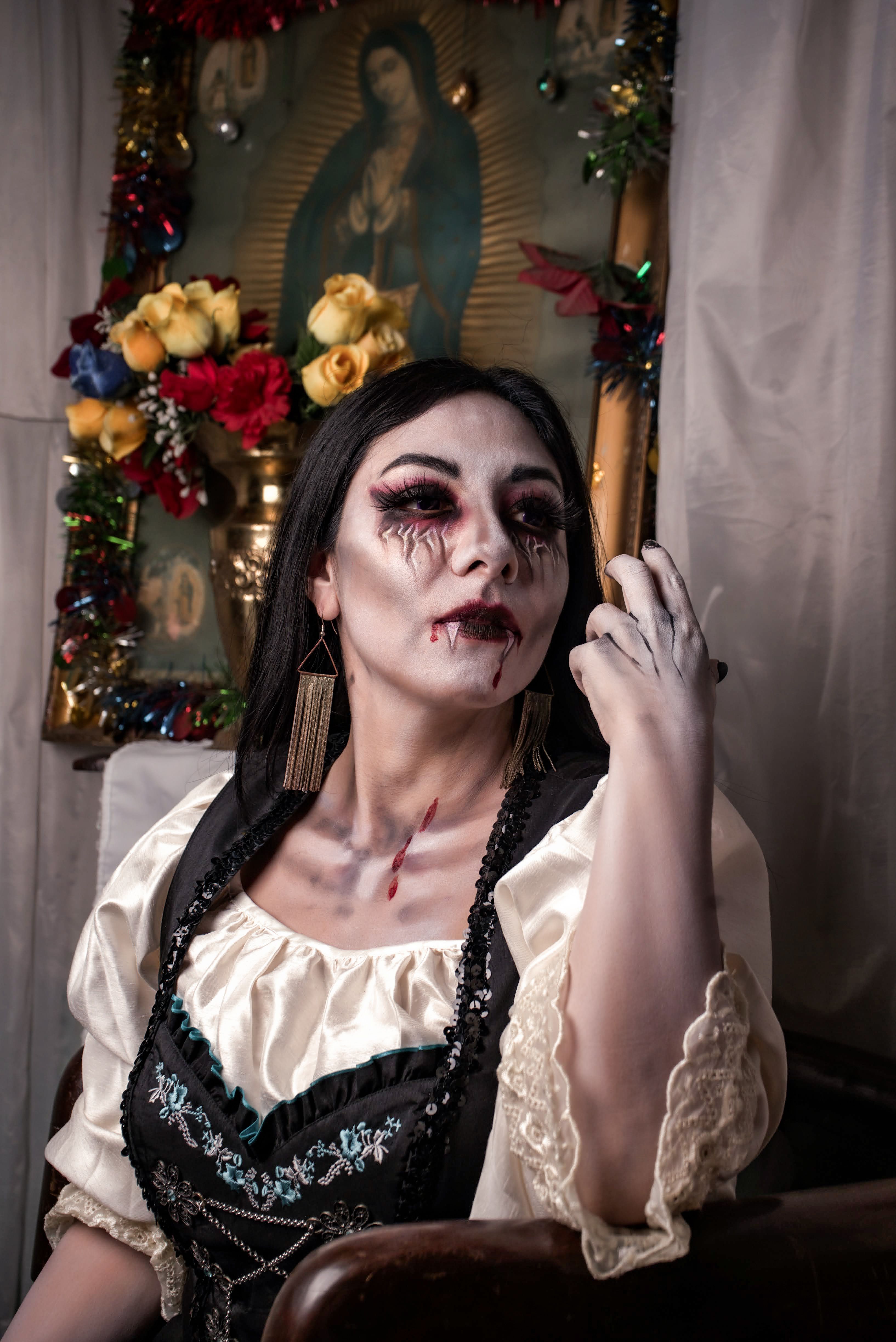 Woman in Dia de los Muertos makeup sits before a decorated altar, evoking cultural and spiritual themes.