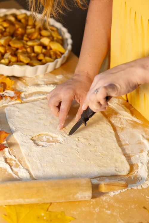 Free Close-up of a woman making apple pie with dough and apples. Stock Photo