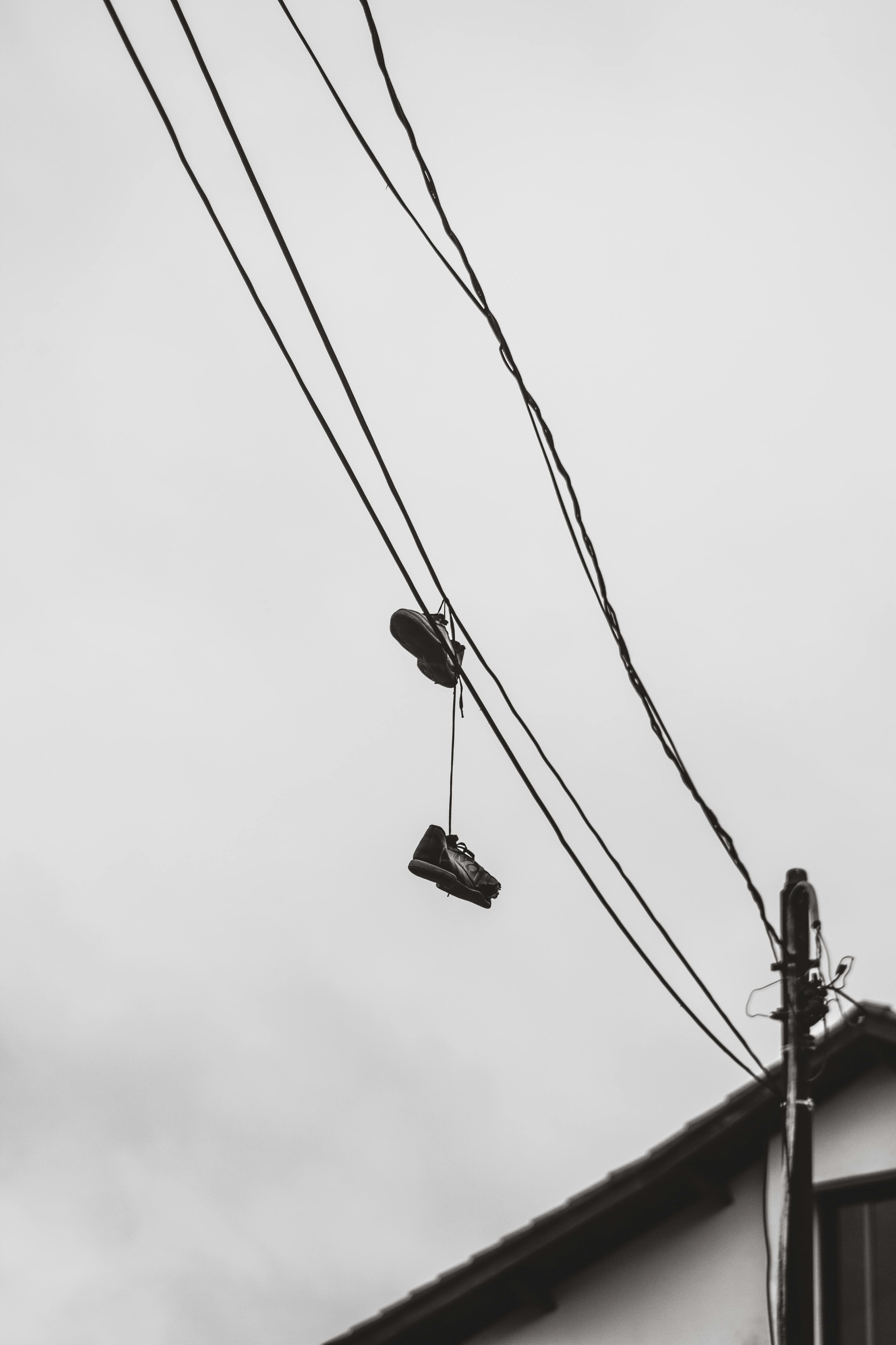 De franc Imatge monocroma amb sabates penjades amb cables contra el cel. Foto d'estoc