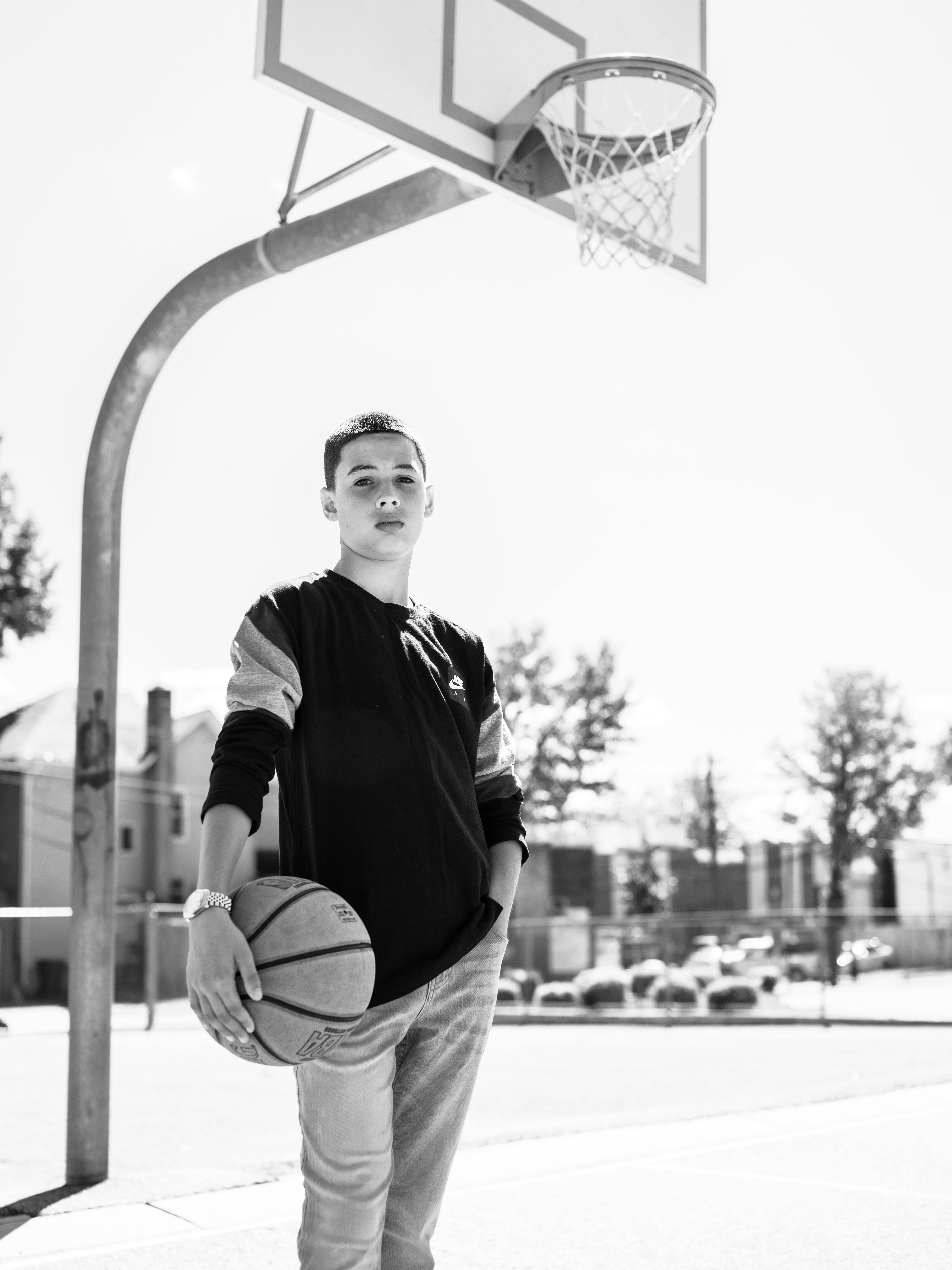 Boy Standing and Holding Basketball Under The Basketball Hoop 