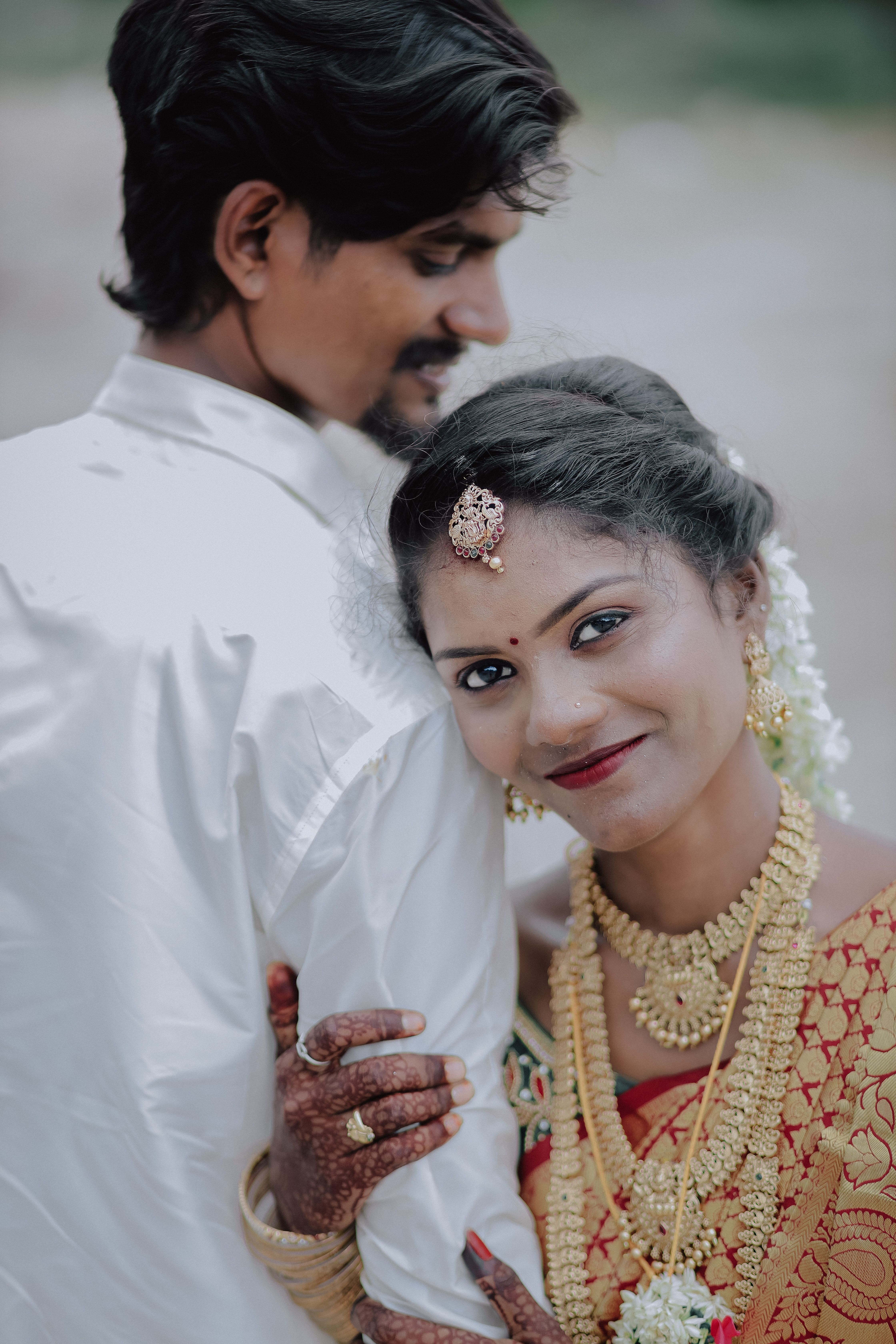 Smiling couple in traditional attire at an outdoor wedding