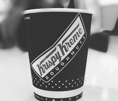 Close-up of Krispy Kreme branded coffee cup in monochrome setting, perfect for business imagery.