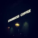 夜晚，星巴克咖啡店闪闪发光的招牌以舒适的氛围照亮了周围