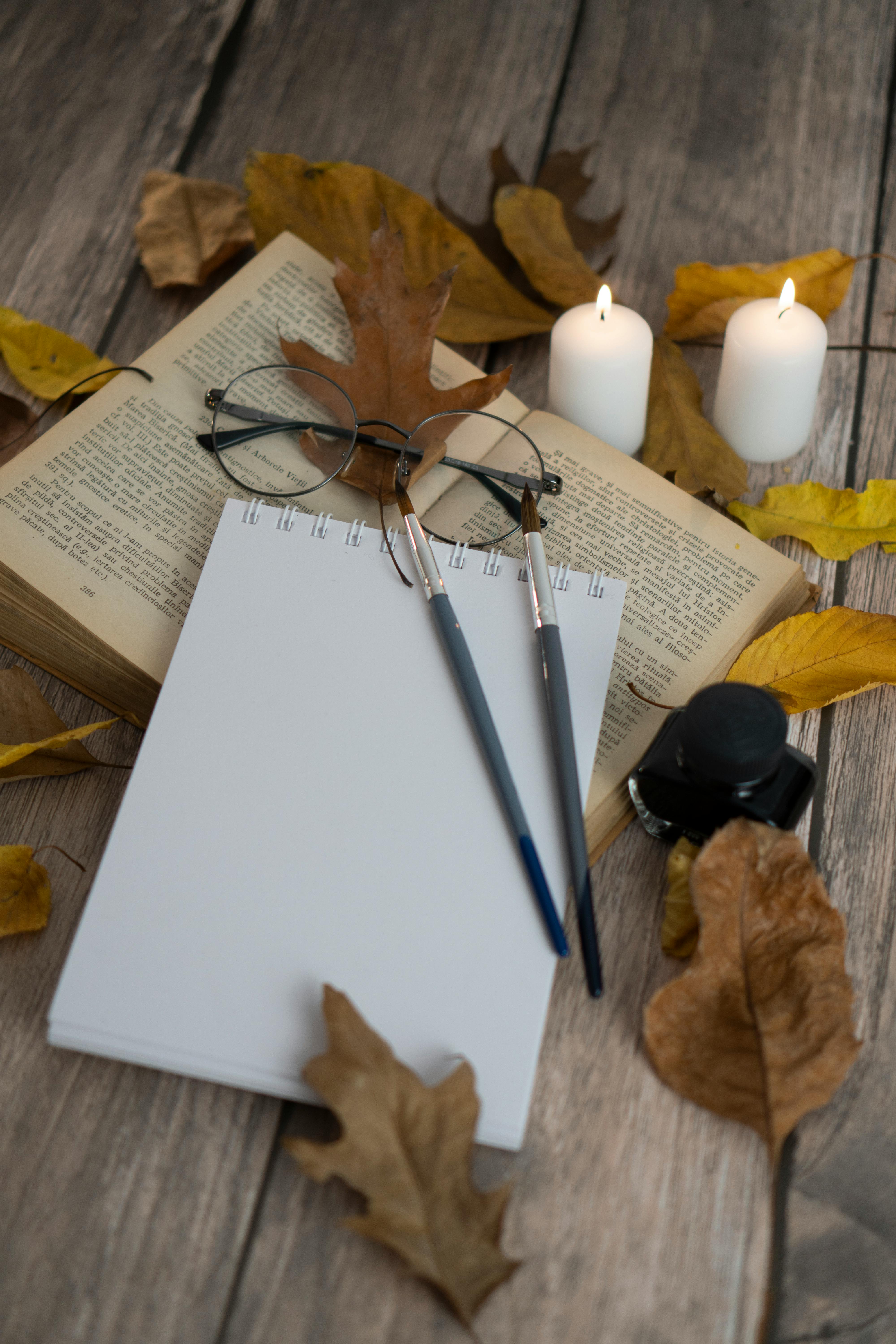 cozy autumn writing setup with candles and leaves