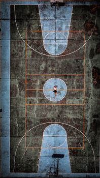 Aerial shot of a worn blue sports court with a lone person in Caracas, Venezuela.