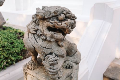 Free Close-up of an intricate stone lion sculpture at a temple in Bangkok, Thailand. Stock Photo