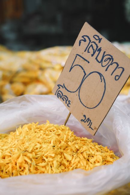 Close-up of vibrant yellow spices with price sign in Bangkok market.