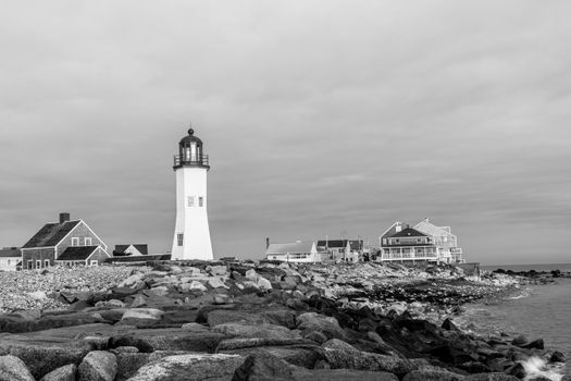 Scenic view of Scituate Lighthouse and rocky coast in Massachusetts, black and white image.