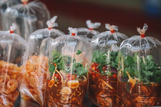 Colorful Thai street food neatly packaged in transparent bags at a Bangkok market.