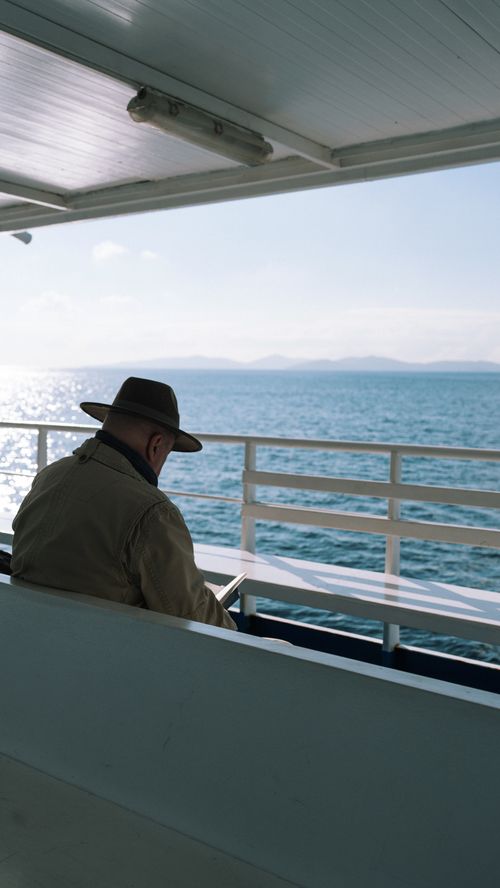 Free A solitary man wearing a hat enjoys a tranquil boat ride overlooking the calm ocean. Stock Photo