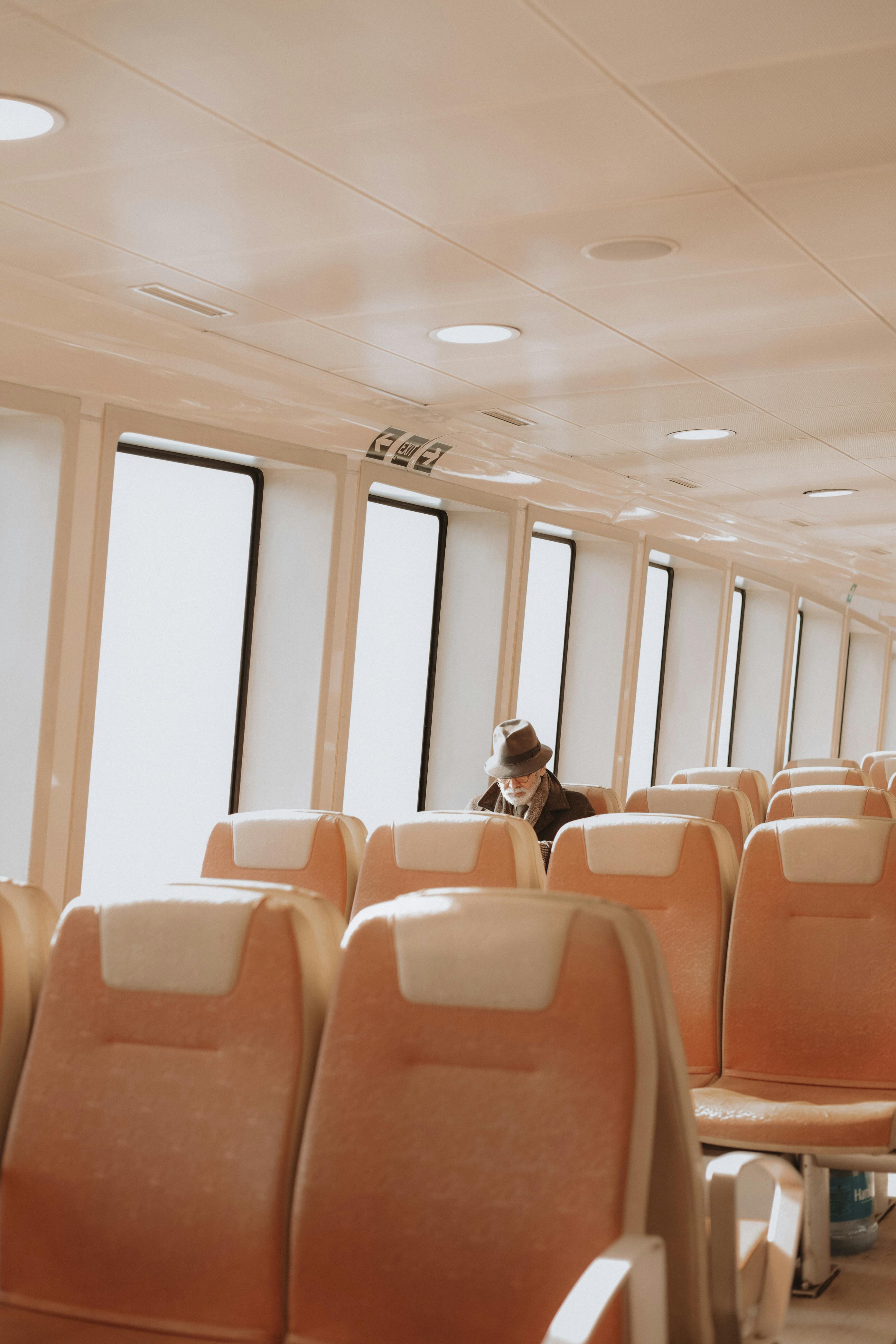 A solitary passenger reads in an empty ferry cabin, bathed in natural light.