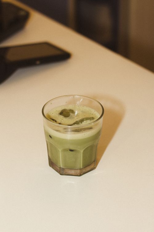 Free A glass of iced matcha latte sits on a table, inviting cool refreshment. Stock Photo
