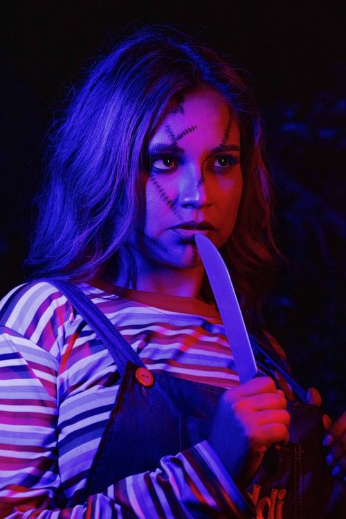 Free A woman dressed in a spooky costume holding a knife with dramatic lighting. Stock Photo