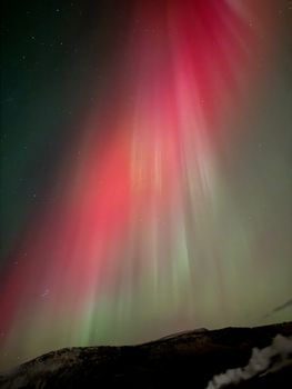Capture of vibrant red and green aurora borealis dancing in the Icelandic night sky.