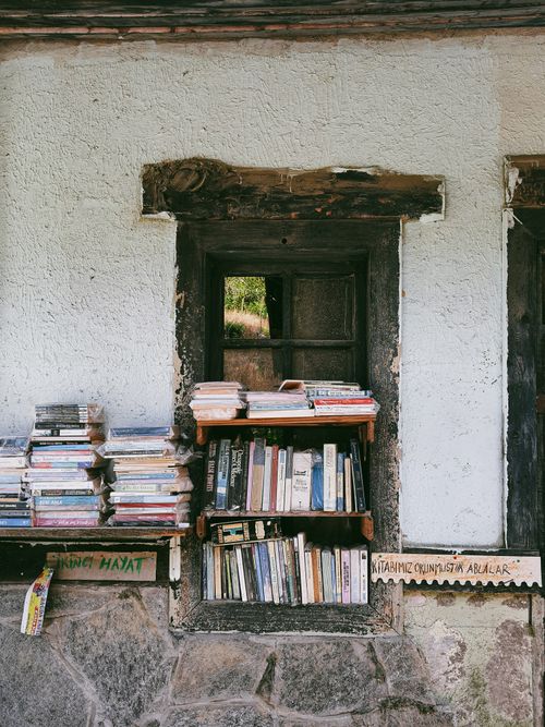 Free Outdoor bookshelf filled with various books against a rustic wall in Rize, Türkiye. Stock Photo