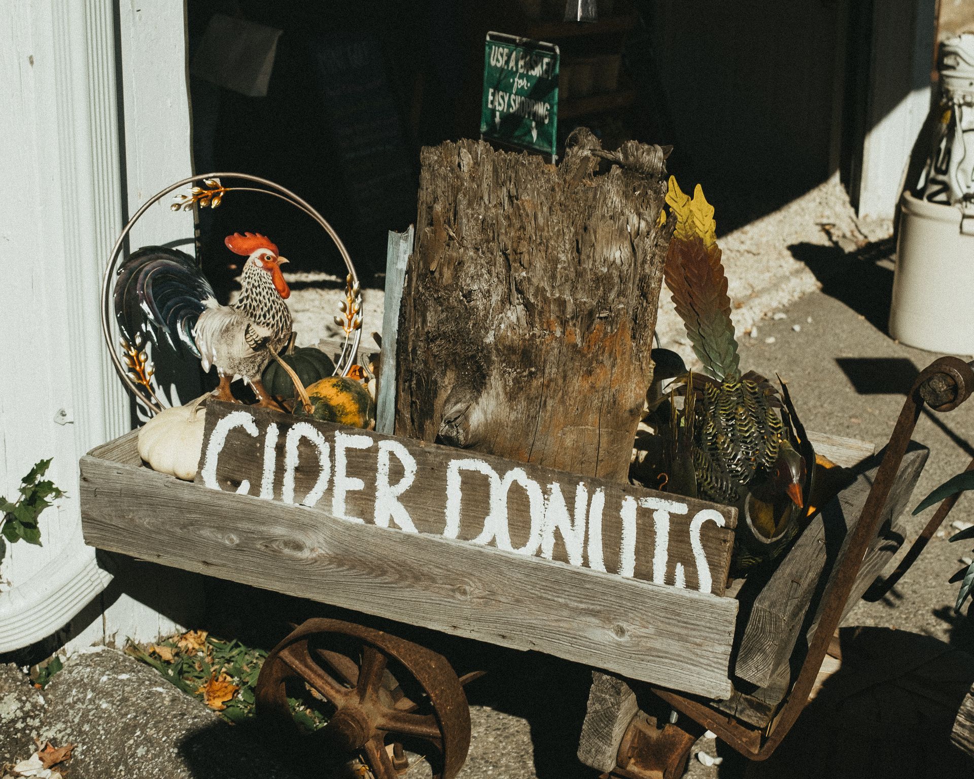 Rustic wheelbarrow with fall decorations and cider donuts sign in Connecticut.