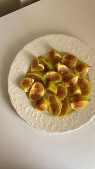 A top view of freshly sliced figs arranged on a decorative white plate.