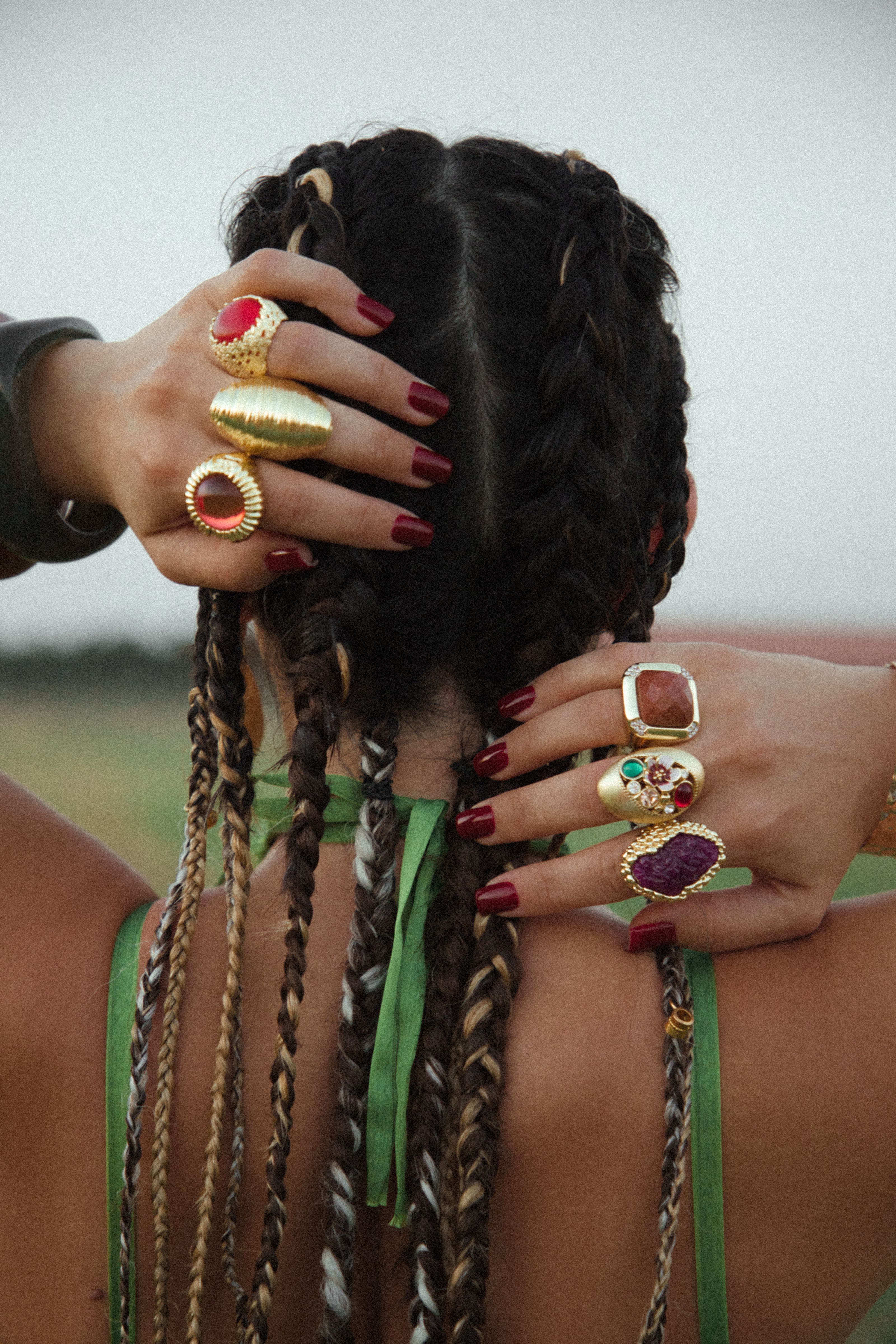 Estilo de cabelo intrincadamente trançado adornado com anéis e unhas ousadas.
