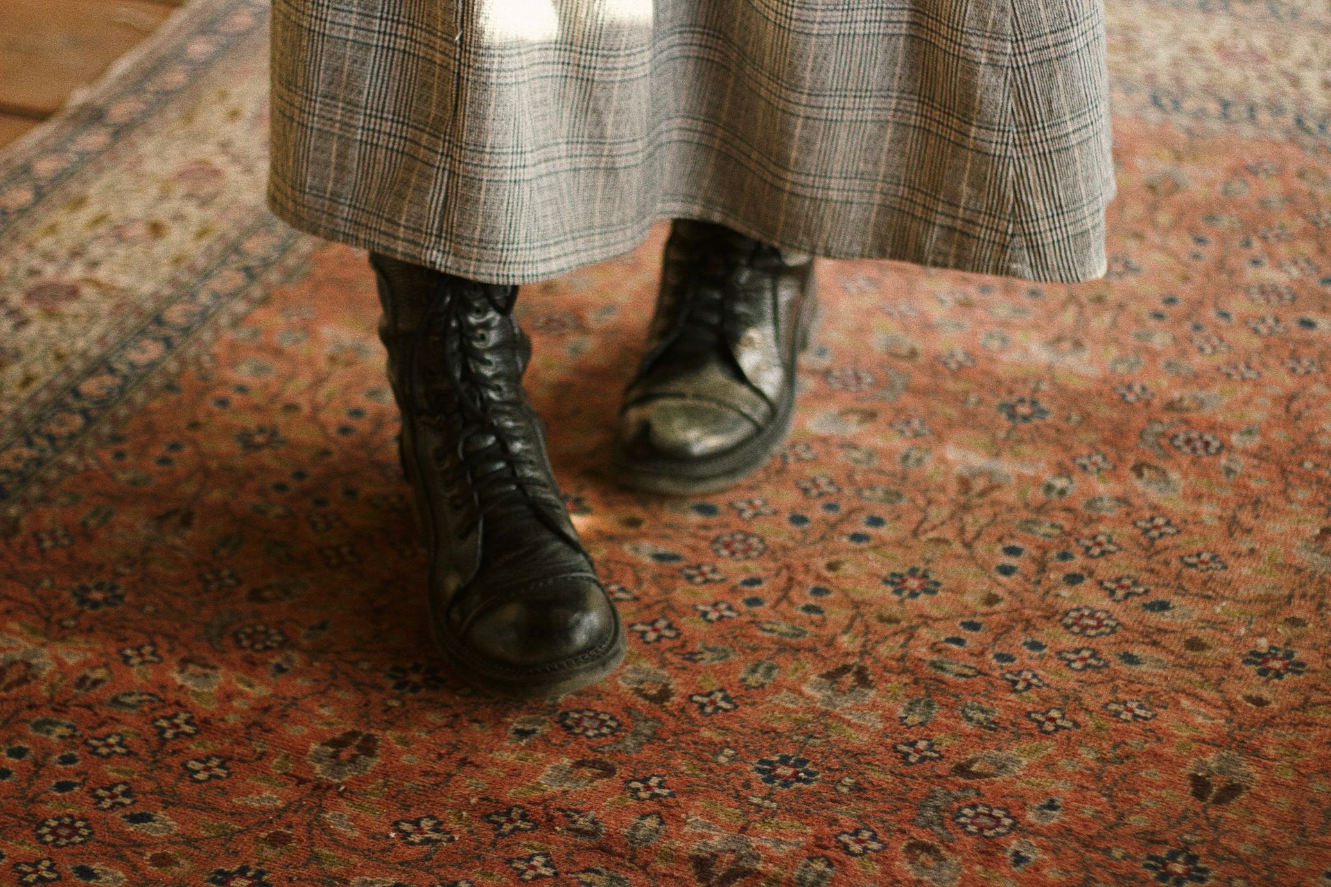 Close-up of vintage combat boots on an intricate Persian rug for a cozy, rustic feel.