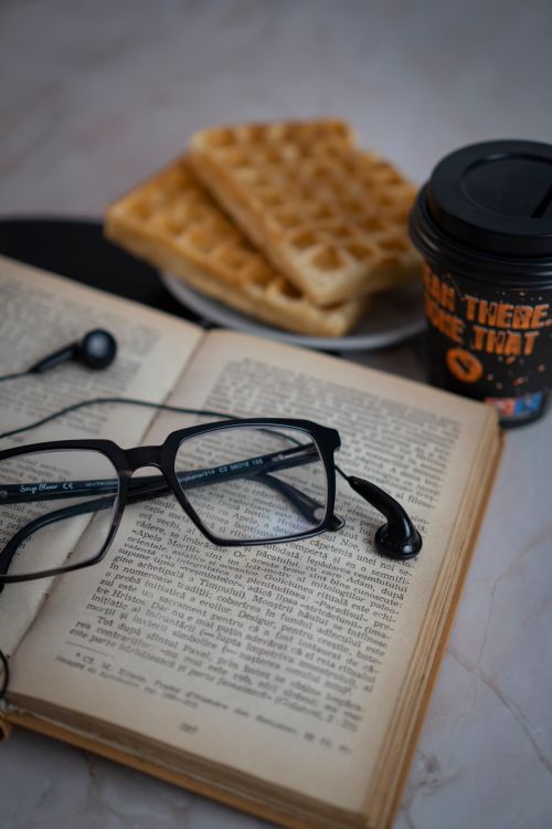 Free An inviting setting with vintage book, waffles, coffee, and glasses. Stock Photo