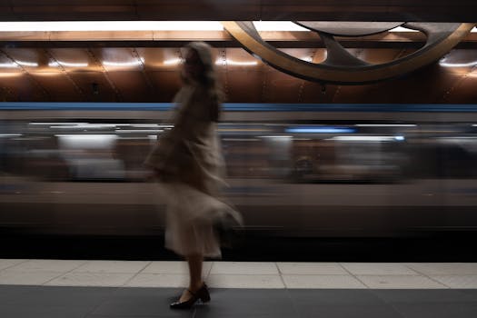 A woman in motion is captured in a Paris metro station with a speeding train in the background.