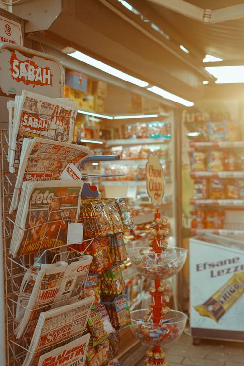 Free Warm-toned view of a convenience store display in Turkey featuring newspapers and snacks. Stock Photo