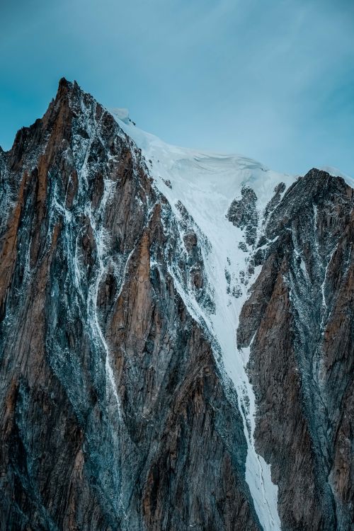 Free Dramatic view of a snow-covered rocky mountain peak under a clear sky. Stock Photo