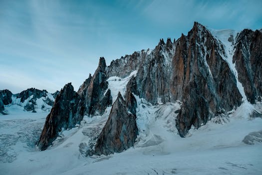 黄昏时分，冰雪覆盖的山脉展现出壮丽景色，突显了戏剧性的岩层