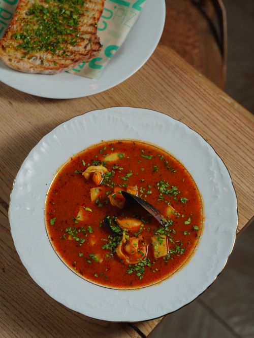 Free Hearty seafood soup served with herb bread on a rustic table setting. Stock Photo