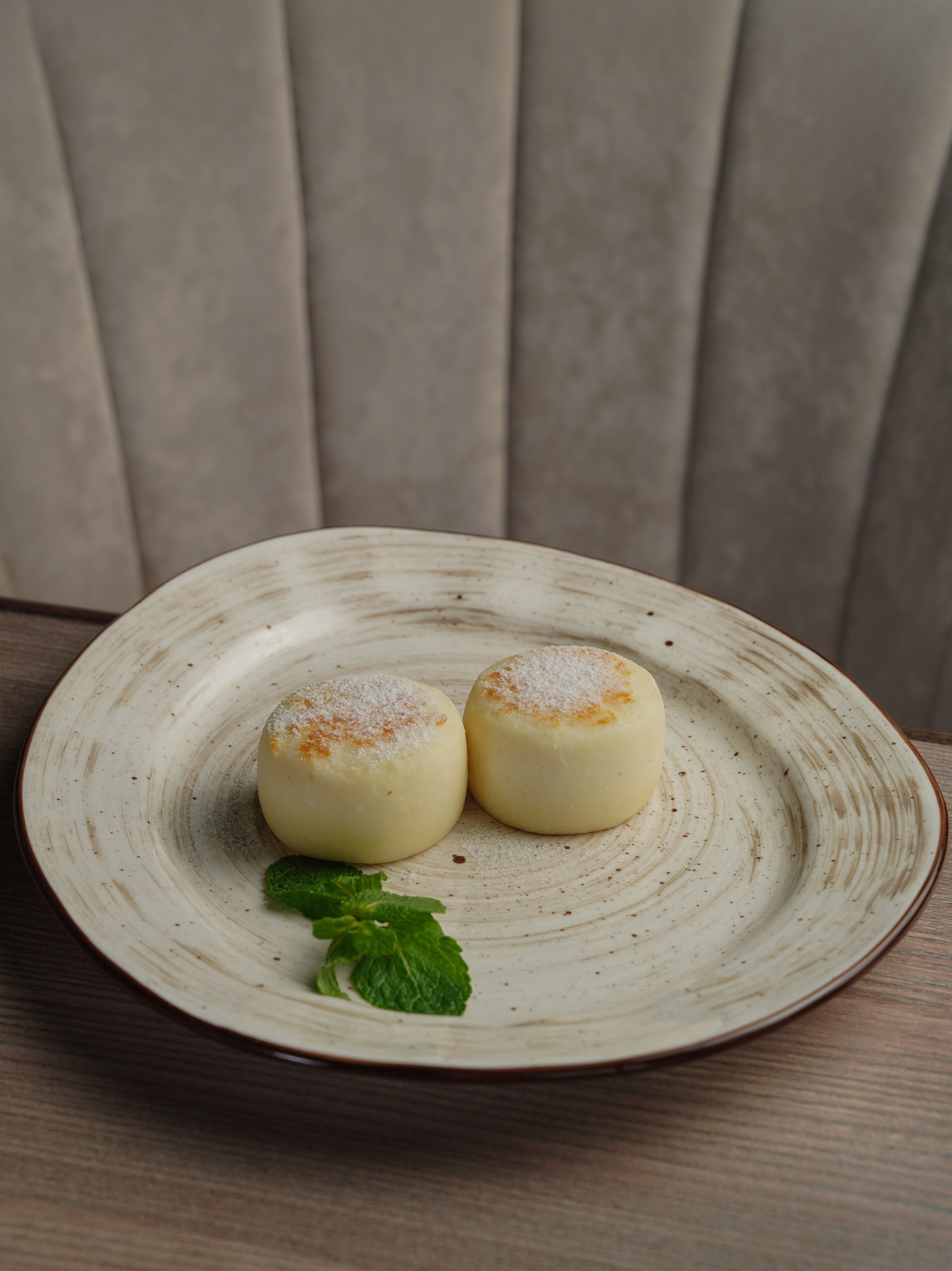 Two creamy cheesecake medallions served on a rustic plate with mint garnish.