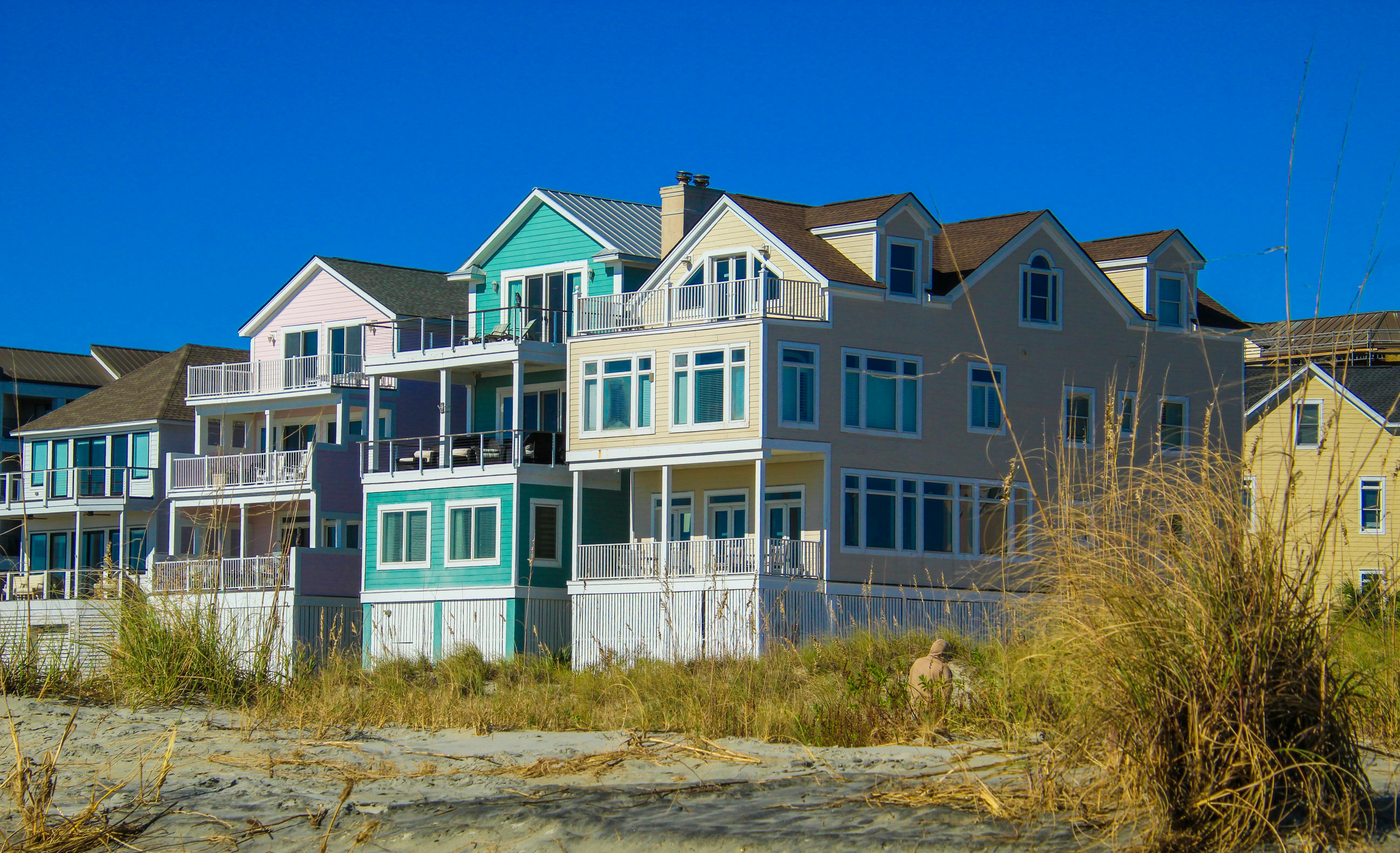 Vibrant beachfront houses on a sunny day, showcasing modern architecture against a clear blue sky.