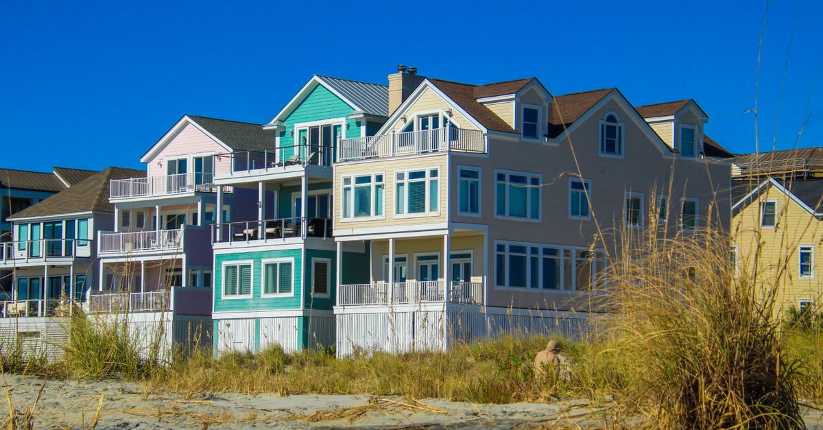Vibrant beachfront houses on a sunny day, showcasing modern architecture against a clear blue sky.
