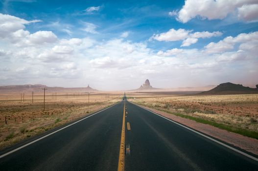 A long straight road leading through the iconic landscape of Monument Valley.