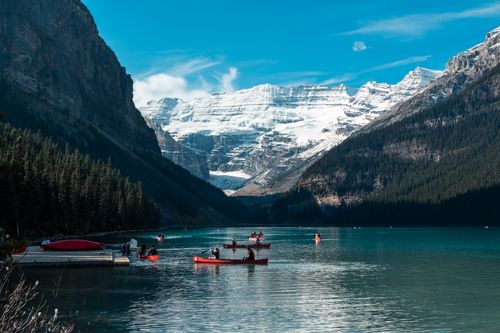 Free Serene view of canoes on Lake Louise surrounded by snow-capped mountains in Banff National Park, Alberta. Stock Photo