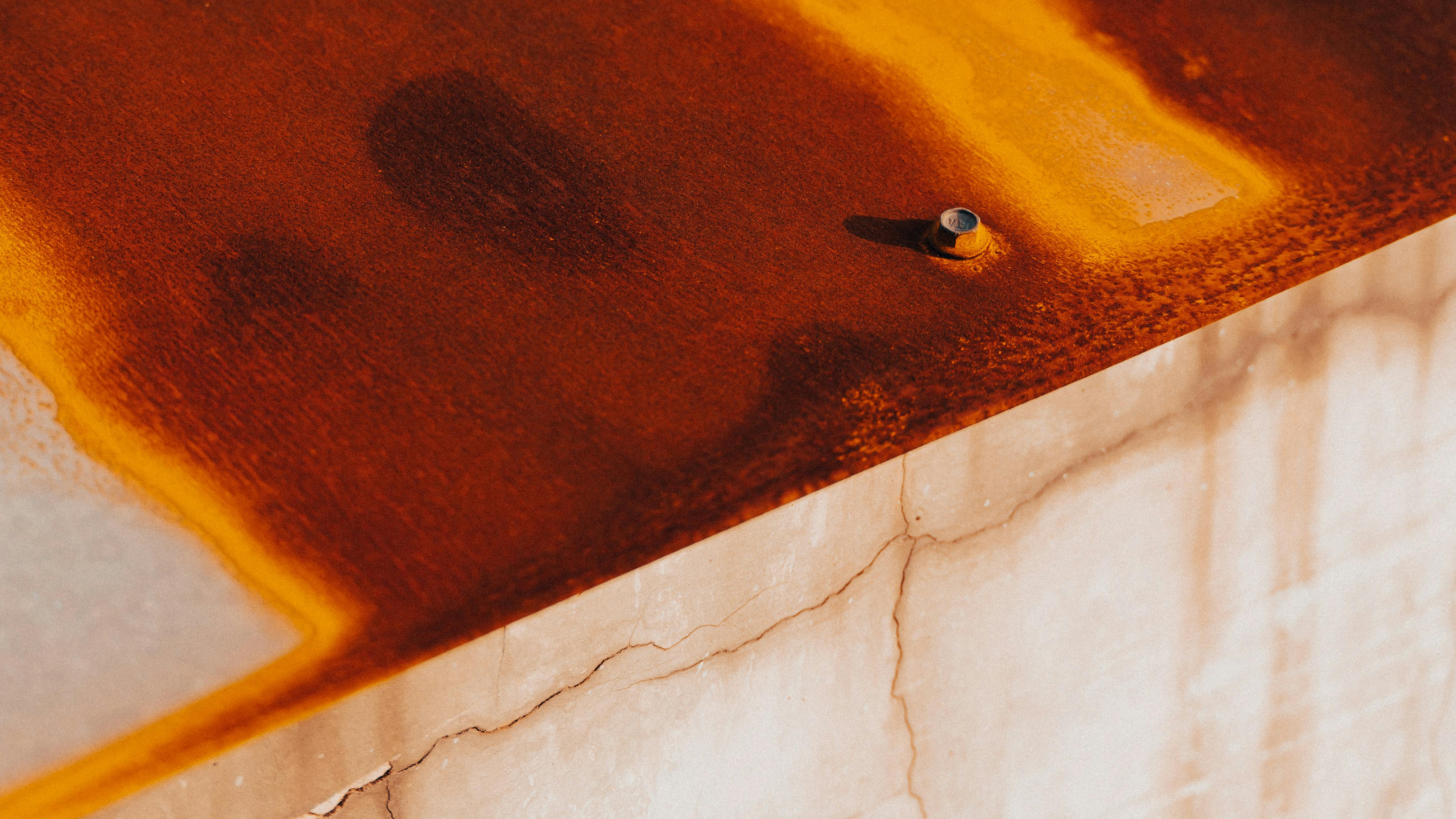 Close-up of a rusted metal surface, highlighting the textured oxidation and bolt detail.