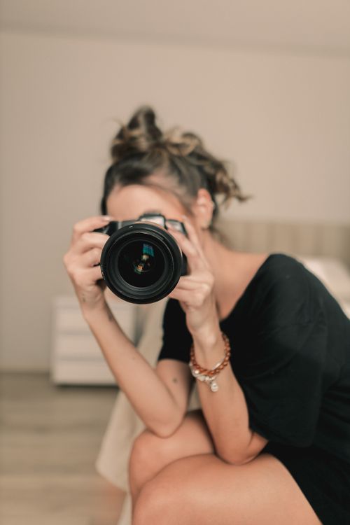 Free Focused woman taking a photo with a DSLR camera indoors, expressing creativity. Stock Photo