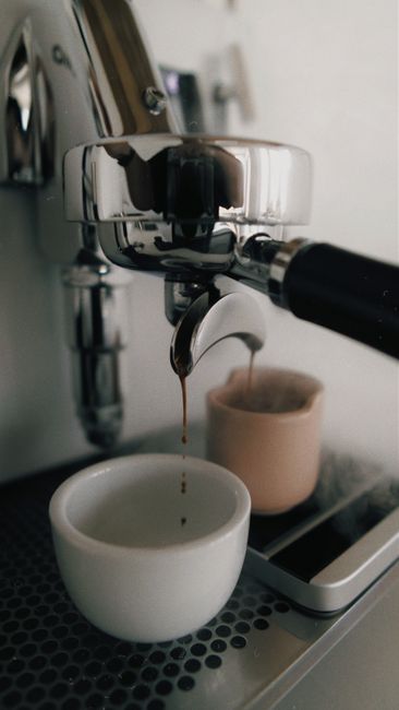 Close-up of an espresso machine brewing coffee, showing two cups, in a modern kitchen setting.