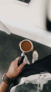 Top-down view of barista holding portafilter with freshly ground coffee.