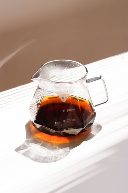 Minimalist photo of coffee in a glass carafe with natural lighting casting shadows