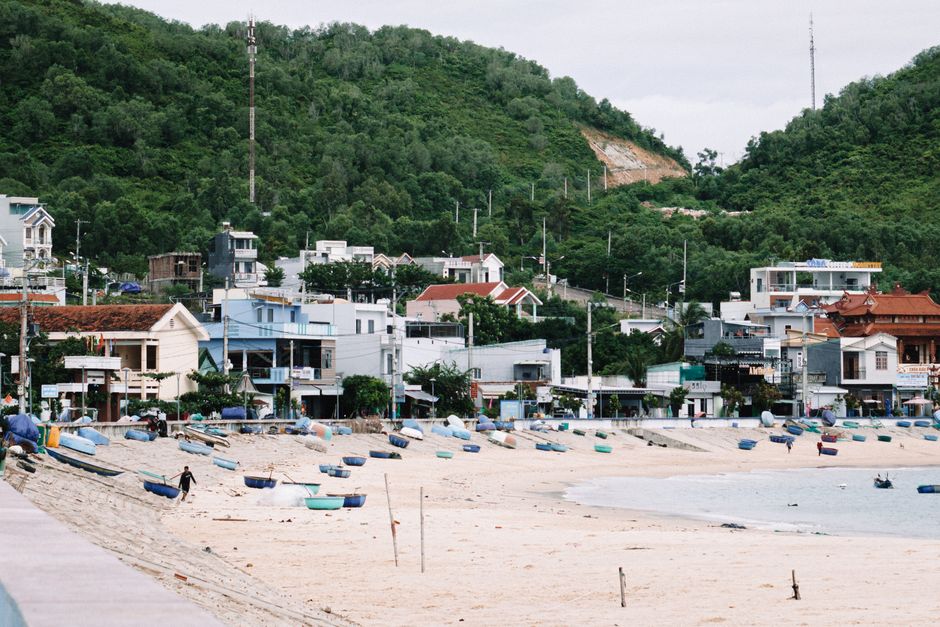 Quiet Binh Ngoc seaside village at midday, simple local eatery, fishing nets drying, anchored boats, authentic and peaceful summer Vietnam, highly detailed