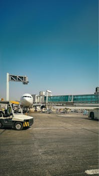 Aircraft parked at Karachi airport apron connected to terminal bridge on a clear day.