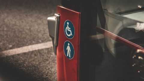 Close-up view of accessibility and elderly symbols on a red city bus.