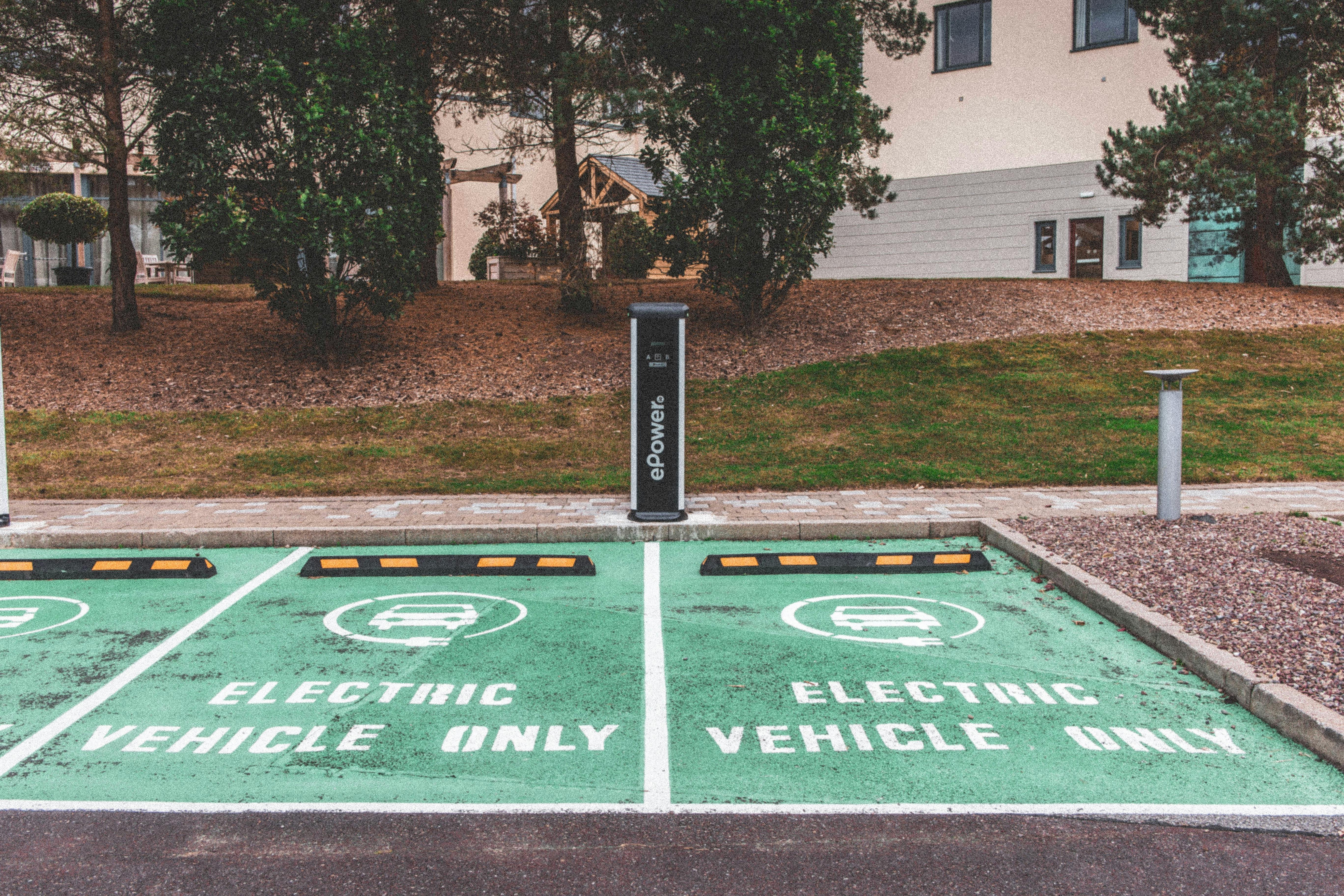 Free Green electric vehicle parking with charging station in urban environment. Stock Photo