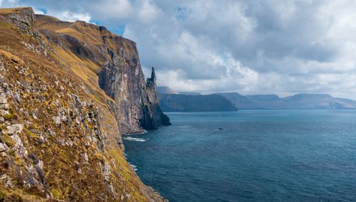 Free Majestic moss-covered cliffs overlooking the Atlantic Ocean in the Faroe Islands under cloud-filled skies. Stock Photo